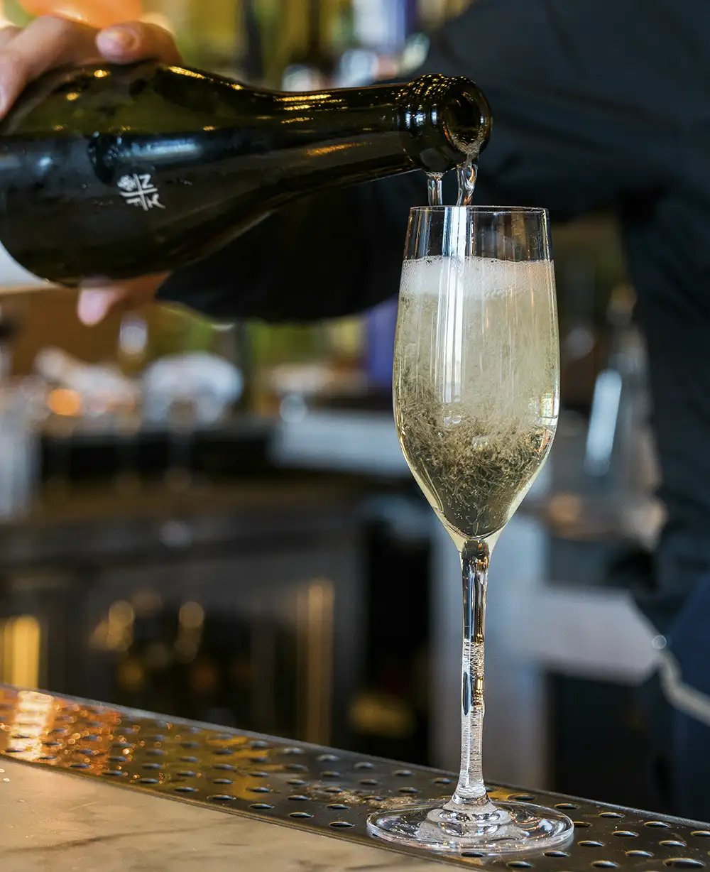 A bartender pouring a glass of sparkline wine or champagne at a bar