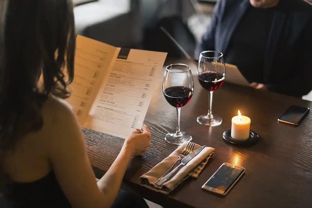 A couple looking at a menu with wine at a restaurant