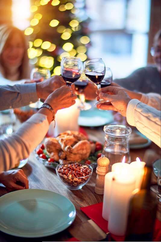 A family toasing wine glasses over a holiday or Thanksgiving dinner