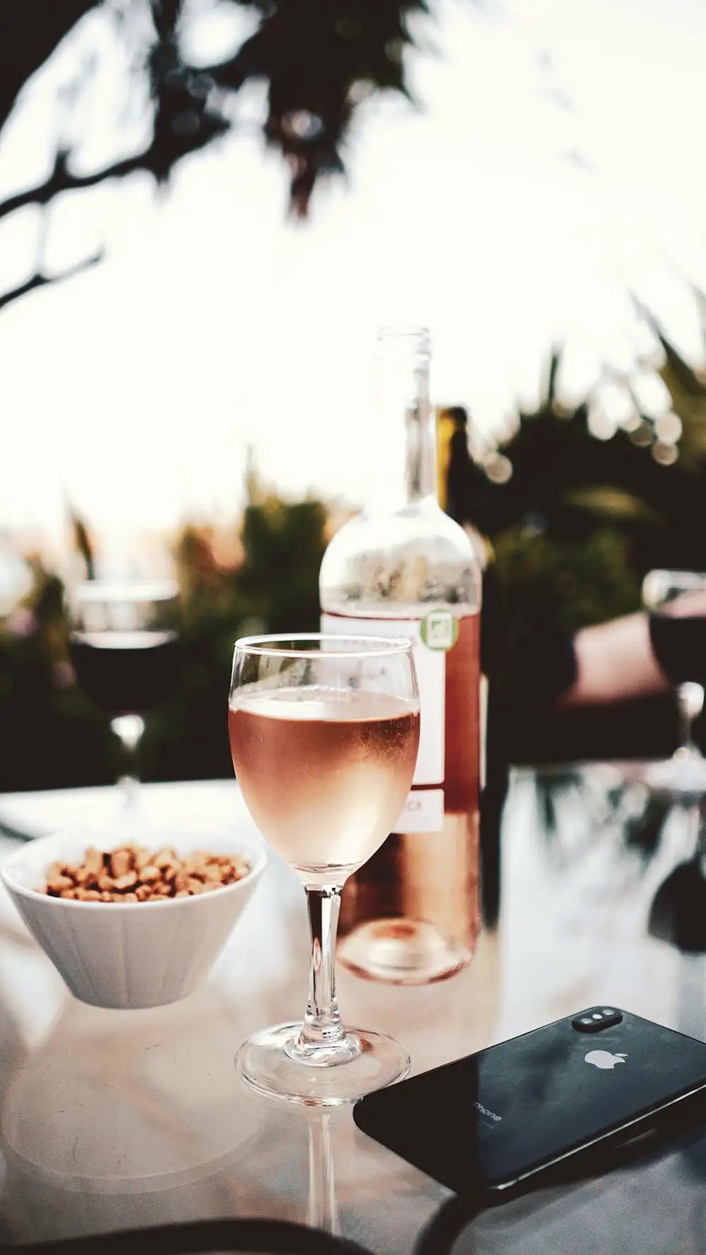 A glass of pink rose wine on an outdoor table at sunset