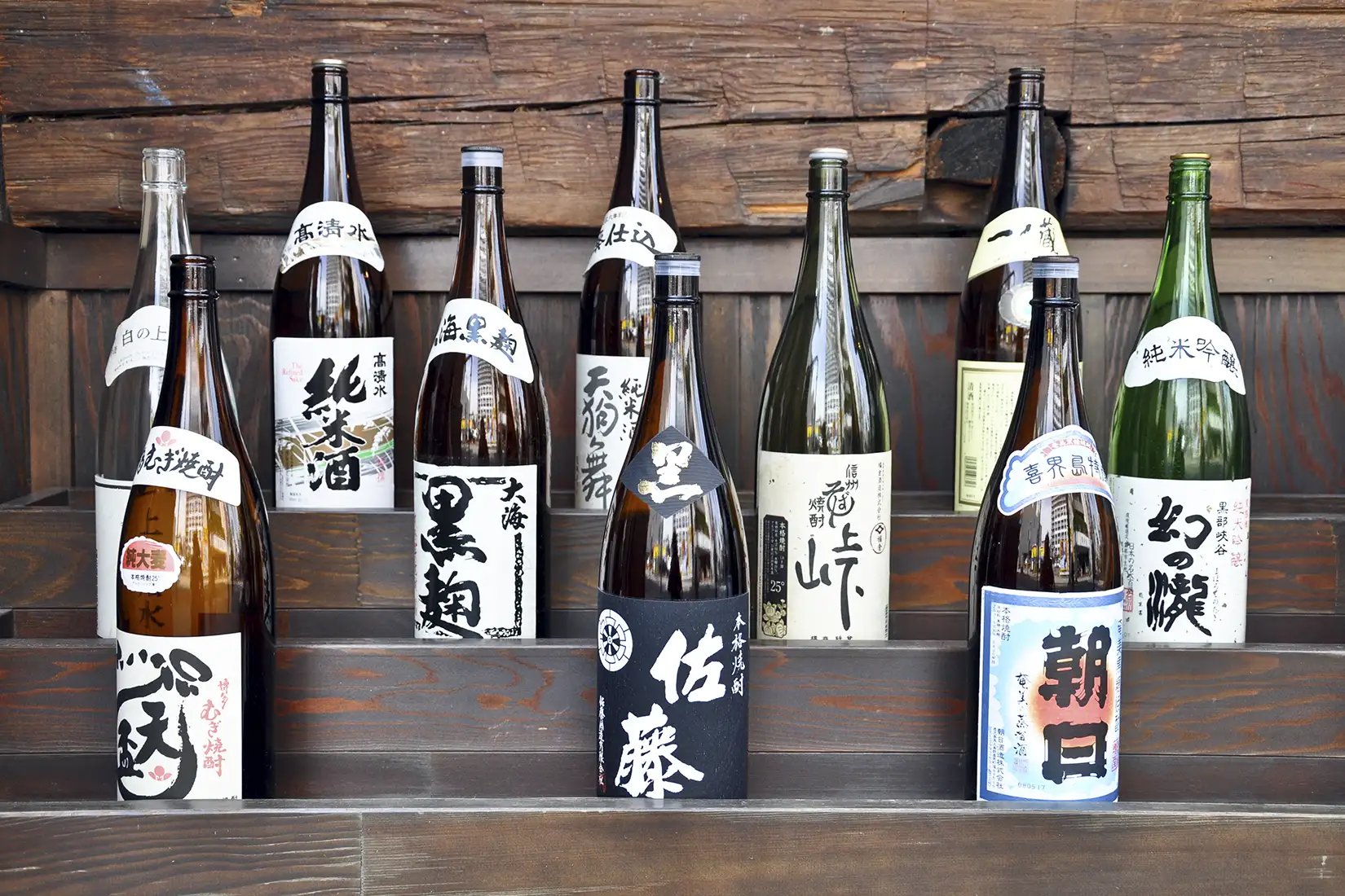 A variety of sake bottles on a wooden shelf