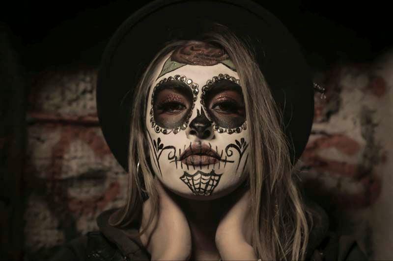 A woman dressed with Mexican sugar skull face painting for Halloween