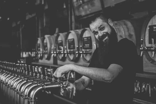 Bartender posing for photo while pouring beer from tap
