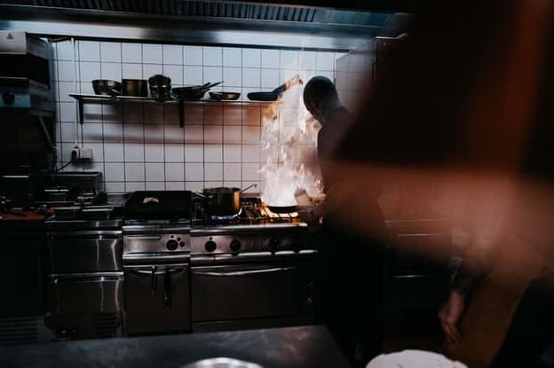 Chef cooking in kitchen on range with flare up