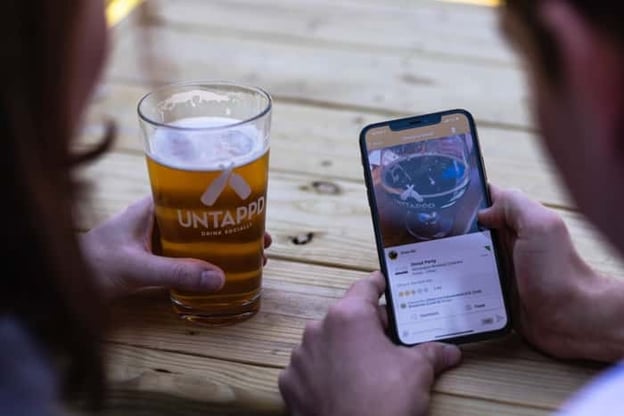 Couple reviewing beer reviews on the Untappd app while at a bar