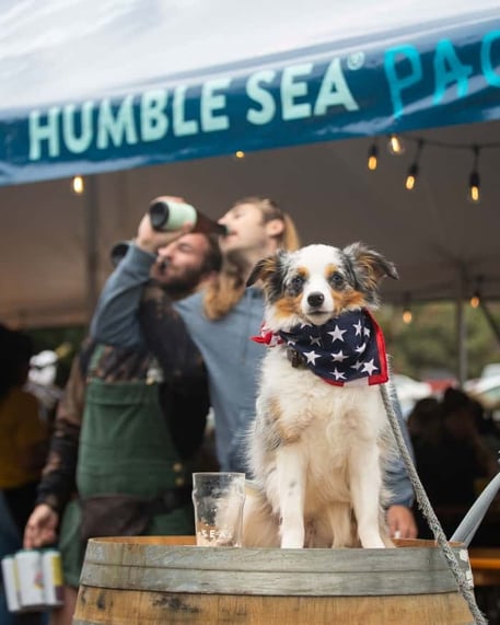 Friends enjoying beer outside with dog on barrel at Humble Sea Brewing Company