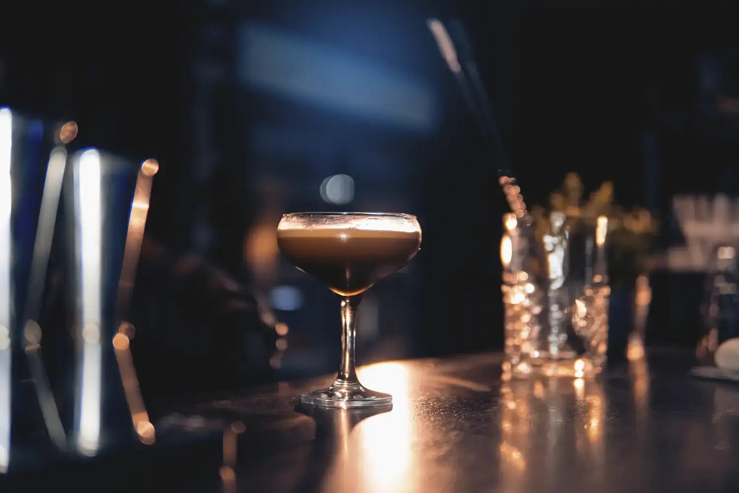 An espresso martini in a glass served on a dark elegant bar