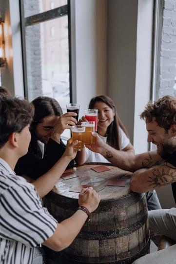 Group of young adults raising beer glasses at brewery