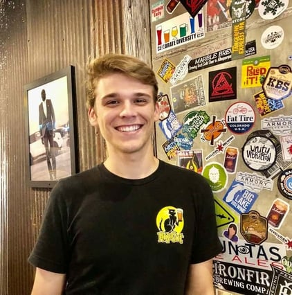 HopCat staff member standing in front of sticker wall