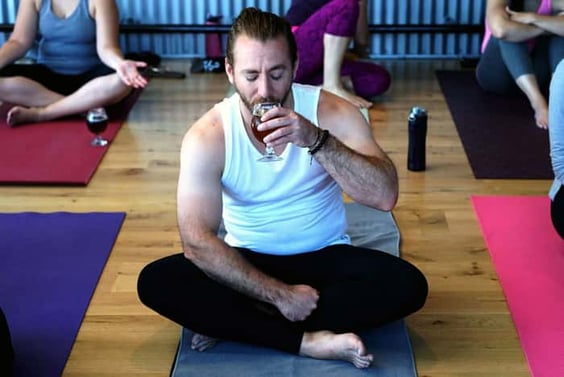 Man enjoying a glass of beer while attending a yoga event