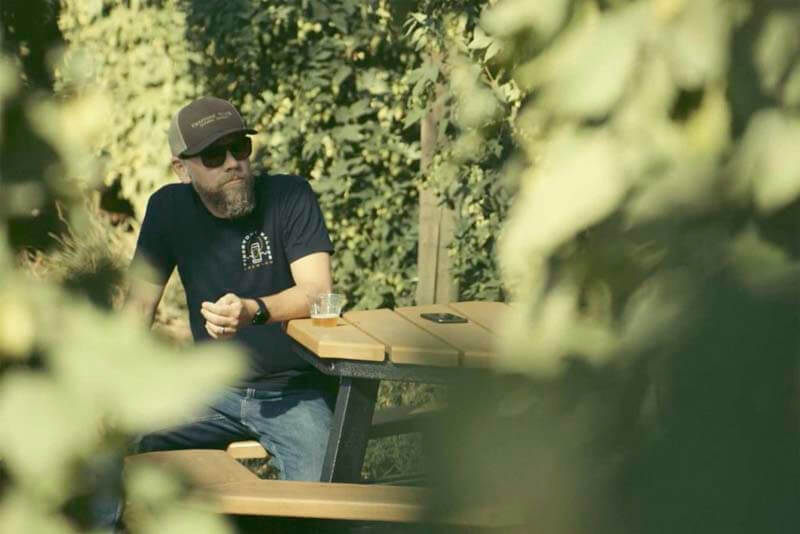Man sitting at outdoor table in hop field at Firestone Walker Brewing Company