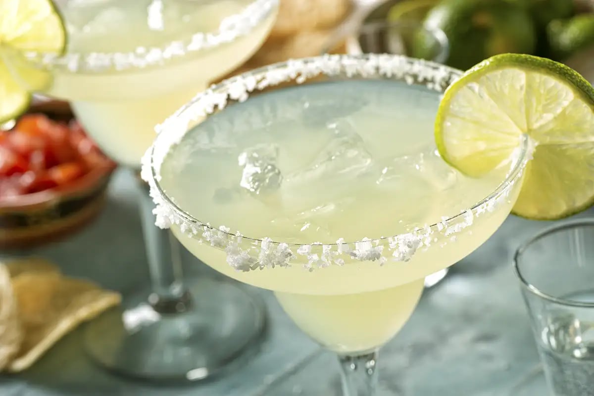 A margarita tequila cocktail served in a classic glass with a salted rim and lime garnish