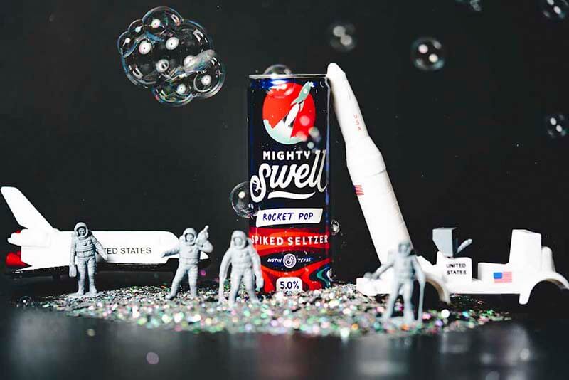 Promotional photo for Mighty Swell Rocket Pop flavored spiked hard seltzer - in a space or astronaut themed environment