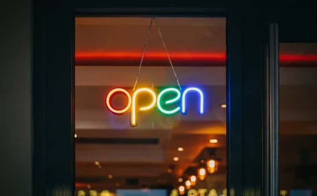 Neon, rainbow colored "Open" sign hanging in bar window