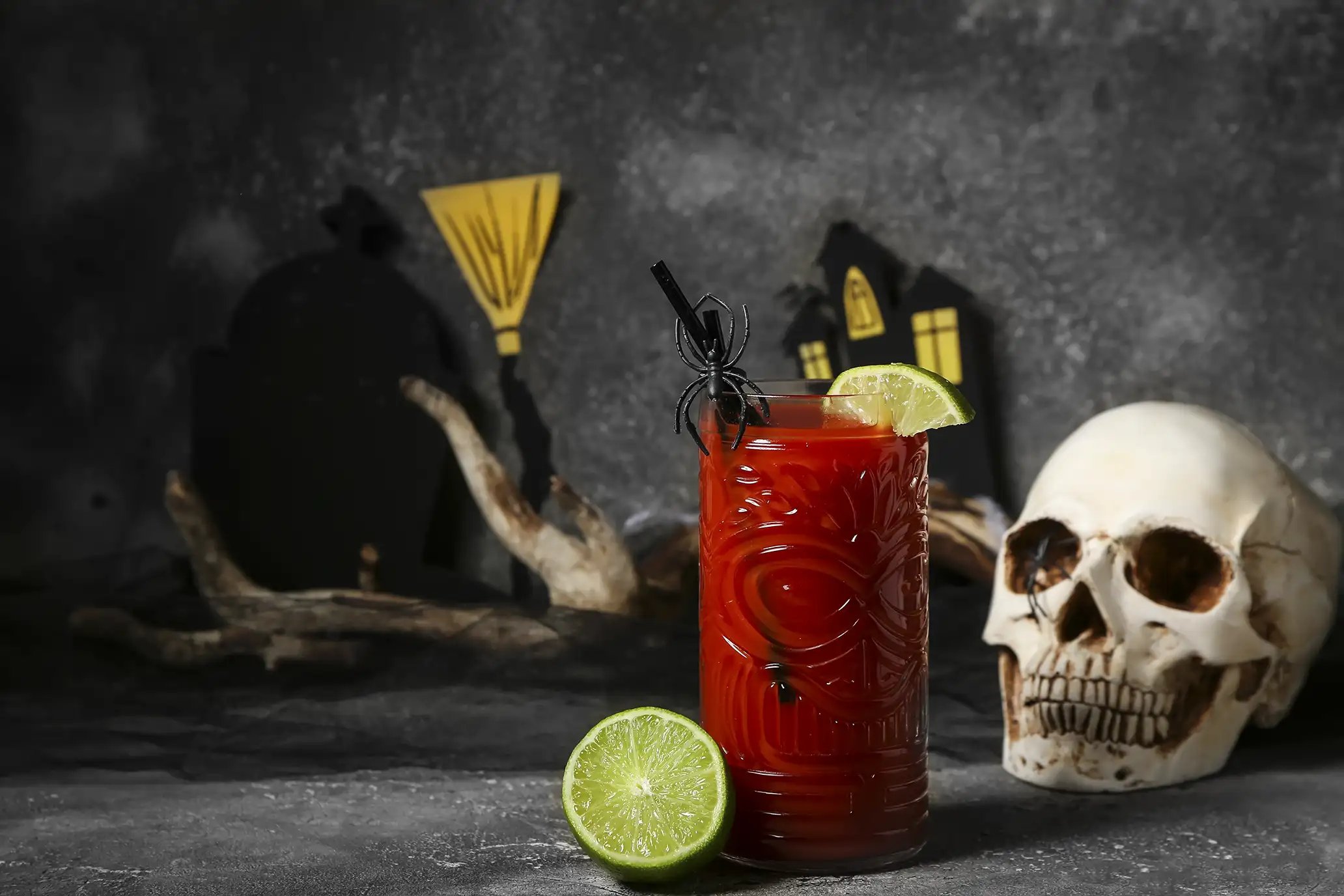 A dark red Halloween themed cocktail resembling blood with Halloween decorations