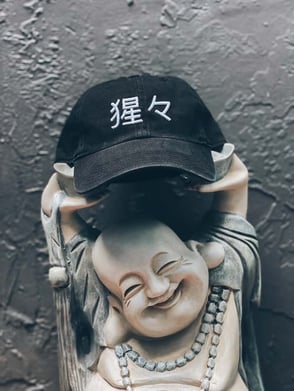 Shojo Beer Company buddah zen mascot holding a hat