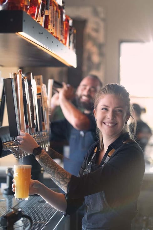 Smiling bartender pouring glass from tap at a bar in Eureka! Restaurant