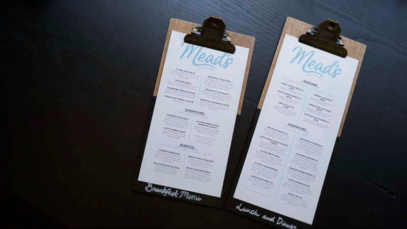 A breakfast menu on clipboard next to a lunch and dinner menu on a clipboard